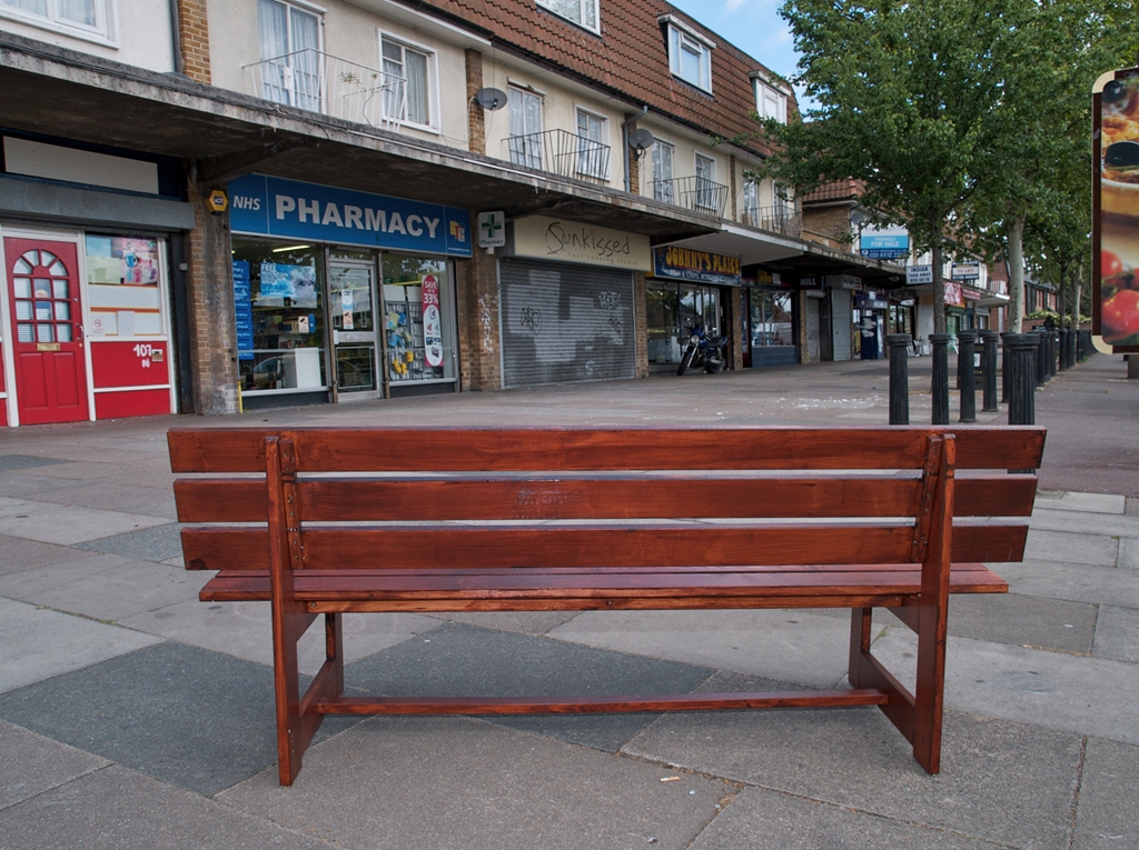 Wooden bench overlooking parade of shops.